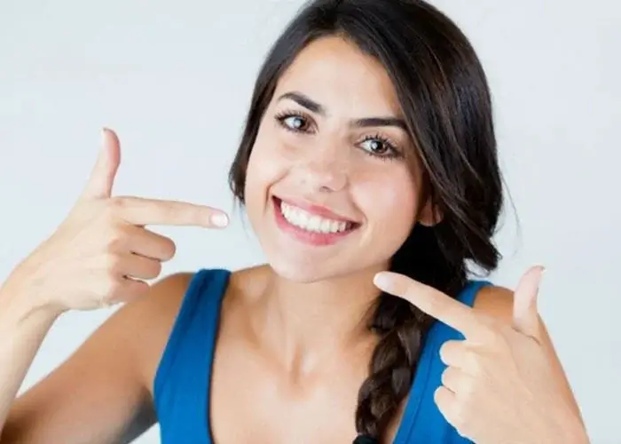 Relaxed patient smiling and pointing at her teeth